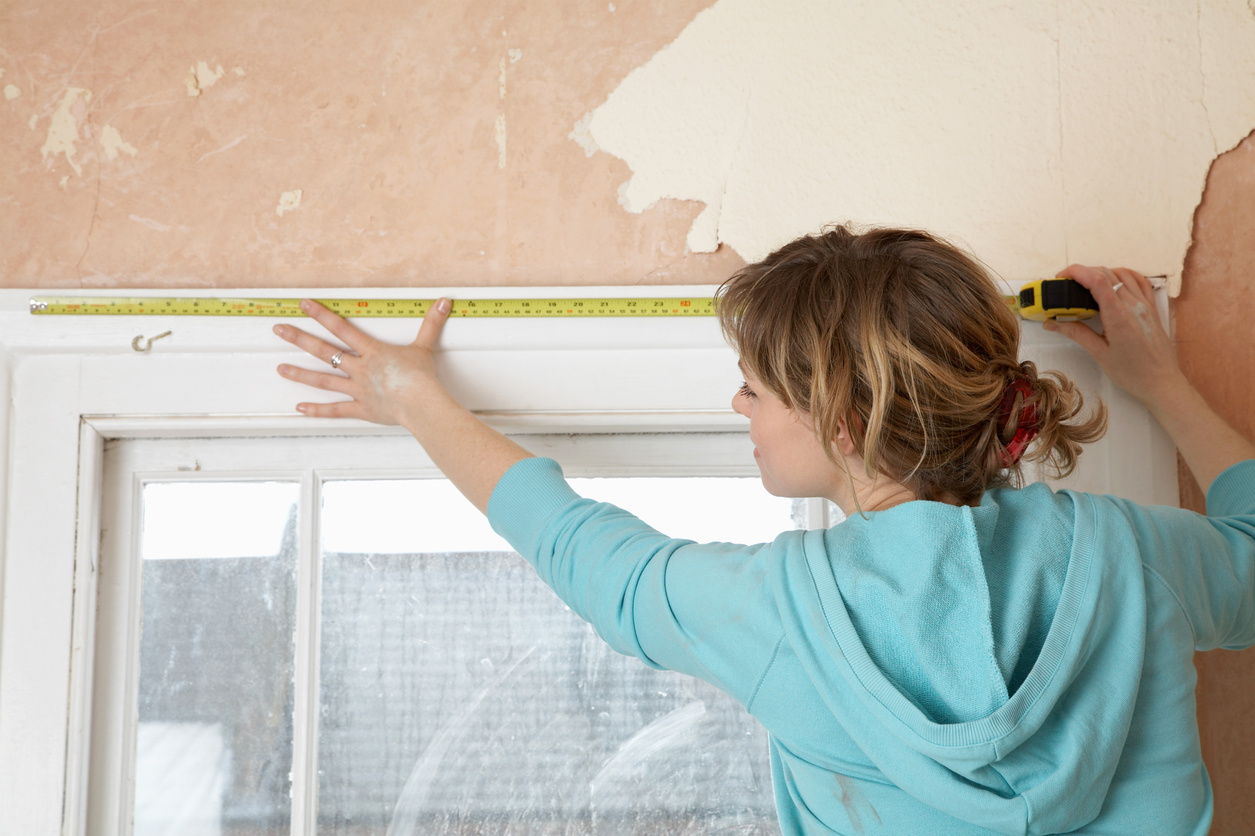 Woman  measuring  interior window frame back view